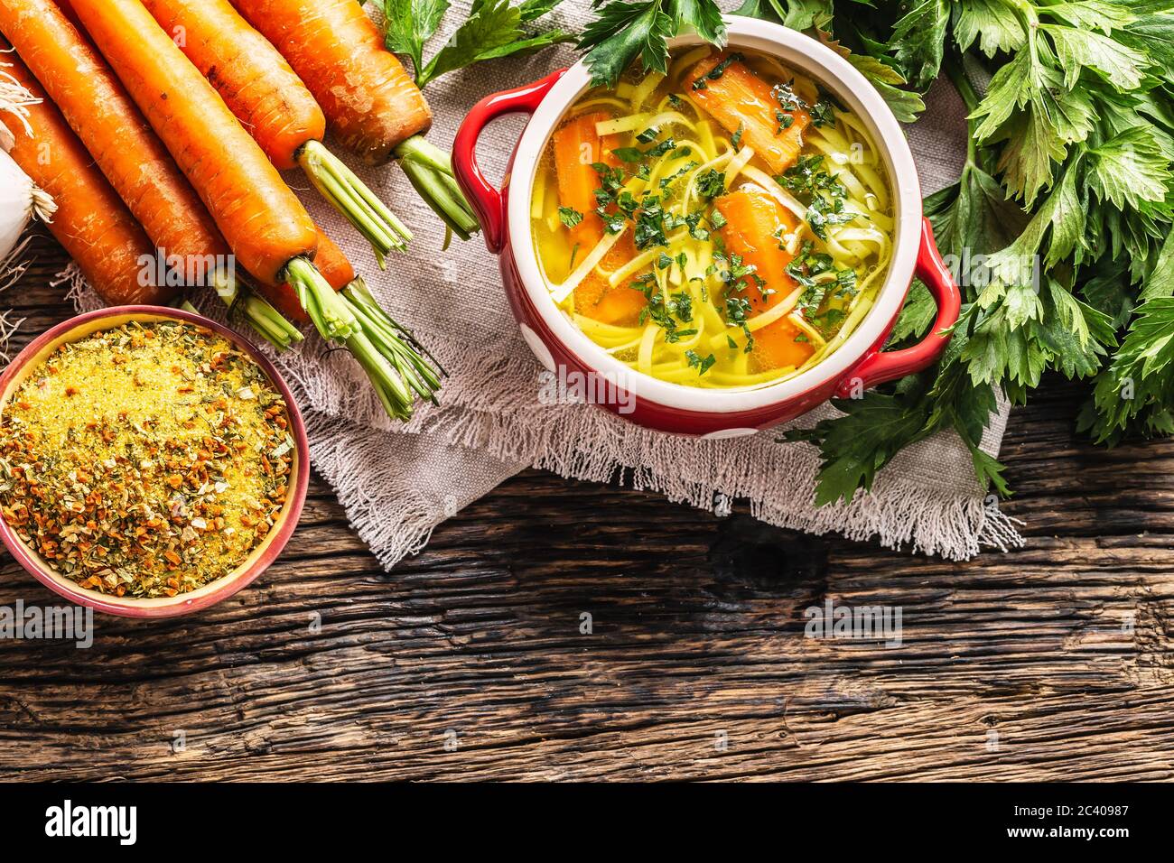 Chicken soup broth in a vintage bowl with homemade noodles carrot onion celery herbs garlic and fresh vegetables. Stock Photo