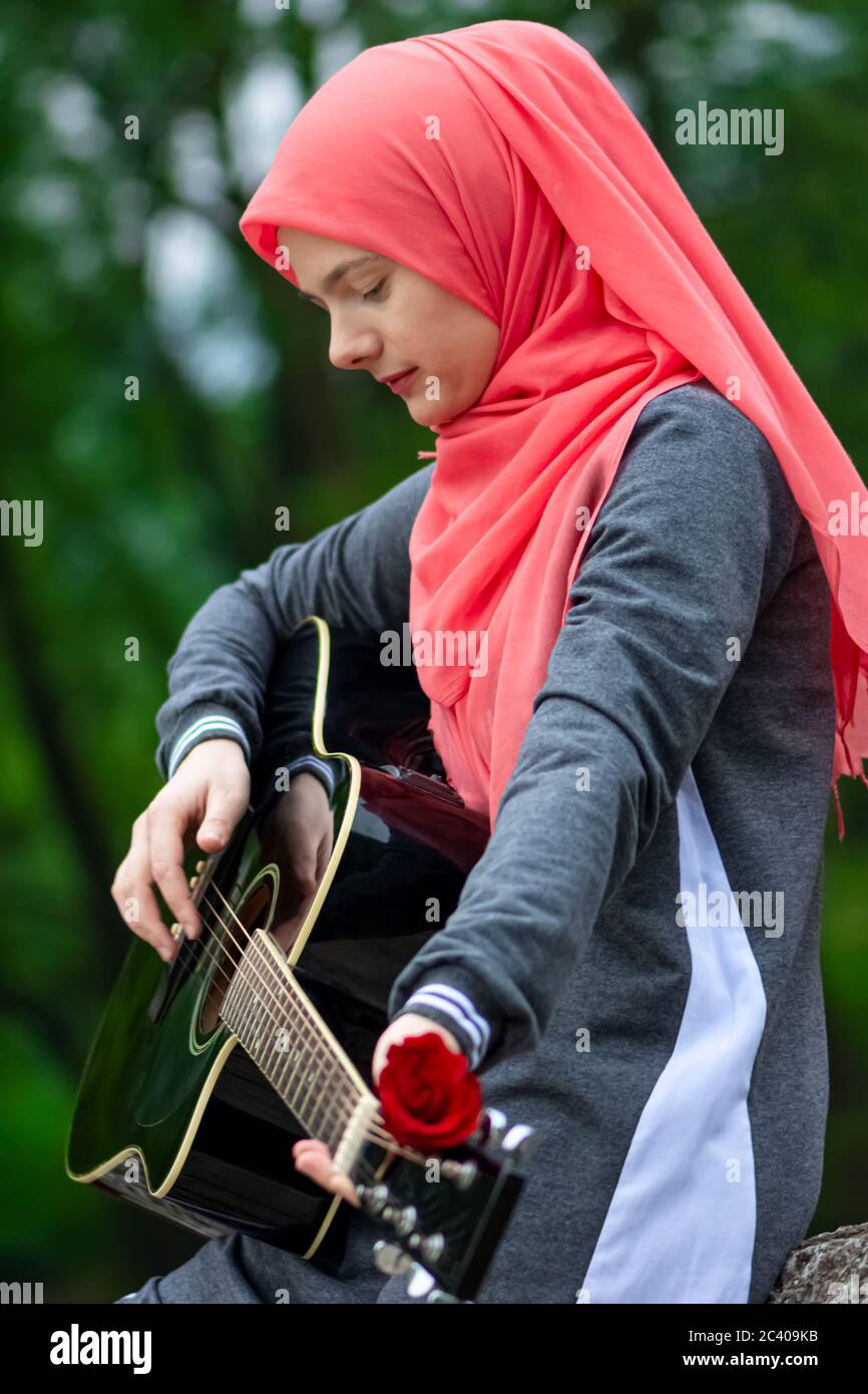 Portrait of pretty Muslim girl trying to play guitar Stock Photo ...