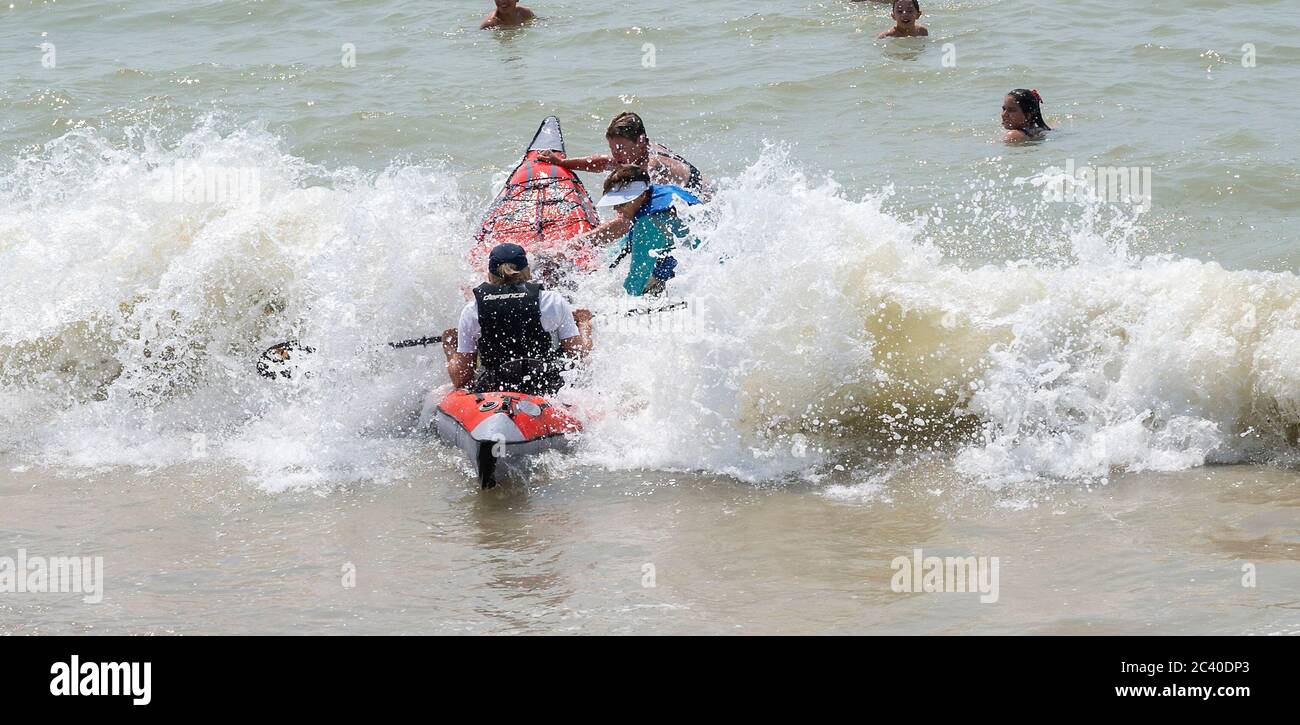 Brighton UK 23rd June 2020 - It's not easy launching an inflatable craft as crowds flock to Brighton beach today as they enjoy the hot sunshine . The weather is forecast to get even warmer over the next few days with temperatures expected to reach over 30 degrees in parts of the South East  : Credit Simon Dack / Alamy Live News Stock Photo