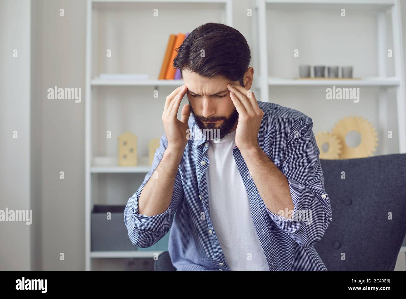 Young man with headache or high blood pressure at home. Stock Photo