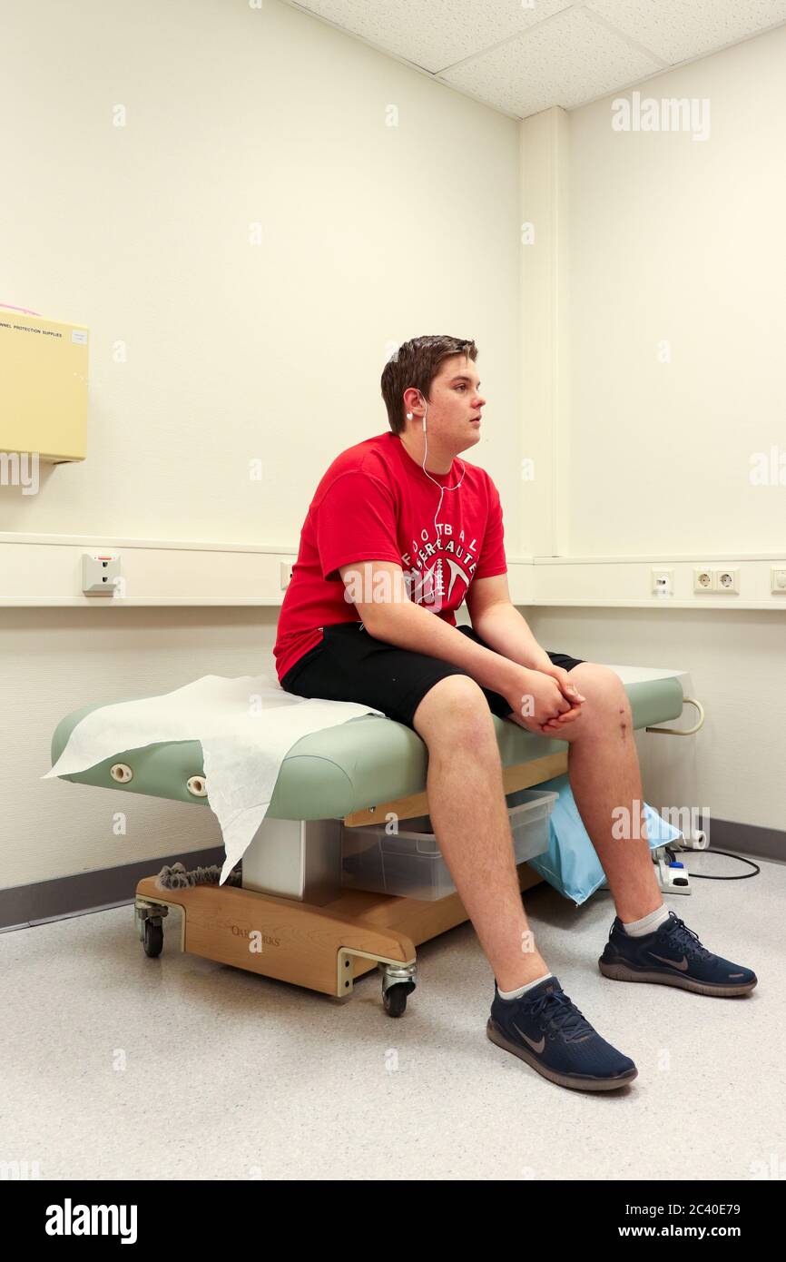 Teenage boy (16) sitting on a hospital bed in a clinic in Germany Stock