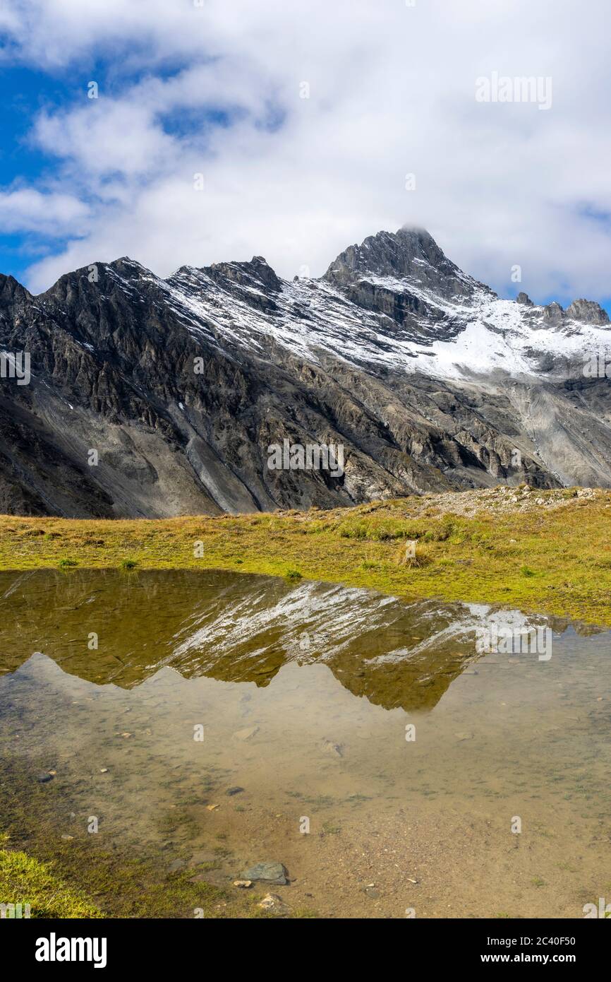 Der Piz Tschütta oder Stammerspitz mit erstem Schnee des Herbstes, Val Maisas, Samnaun, Kanton Graubünden. Spiegelung im Roten Seeli unterhalb des Ros Stock Photo