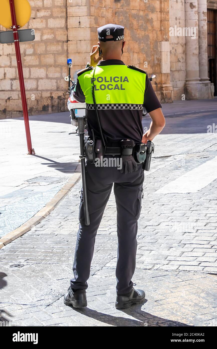Back view of Spanish police  with 'Local Police' logo emblem on uniform maintain public order in the streets of Jaen, Spain Stock Photo