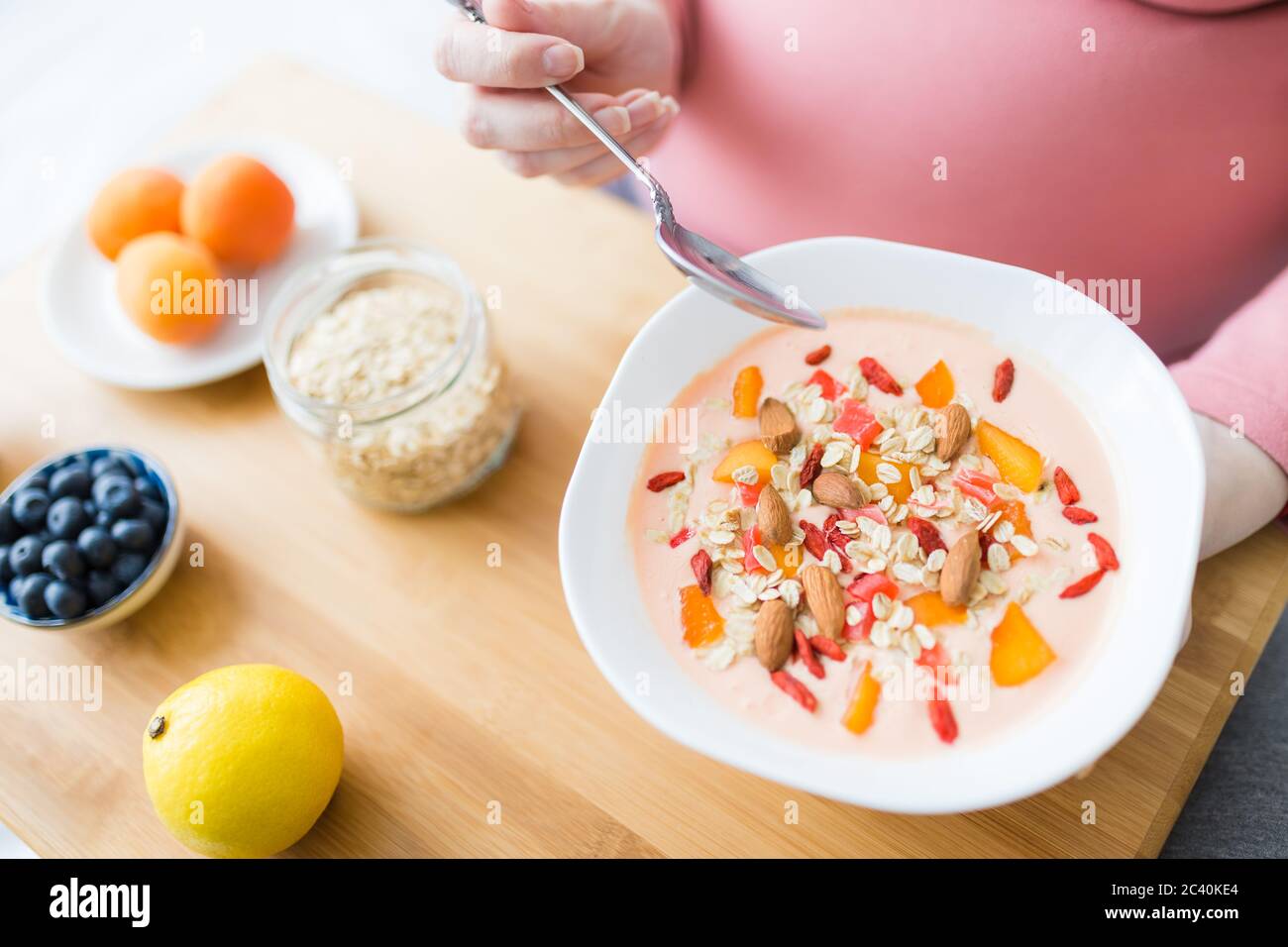 Female sitting on sofa and eating fresh muesli. Pregnancy and healthy