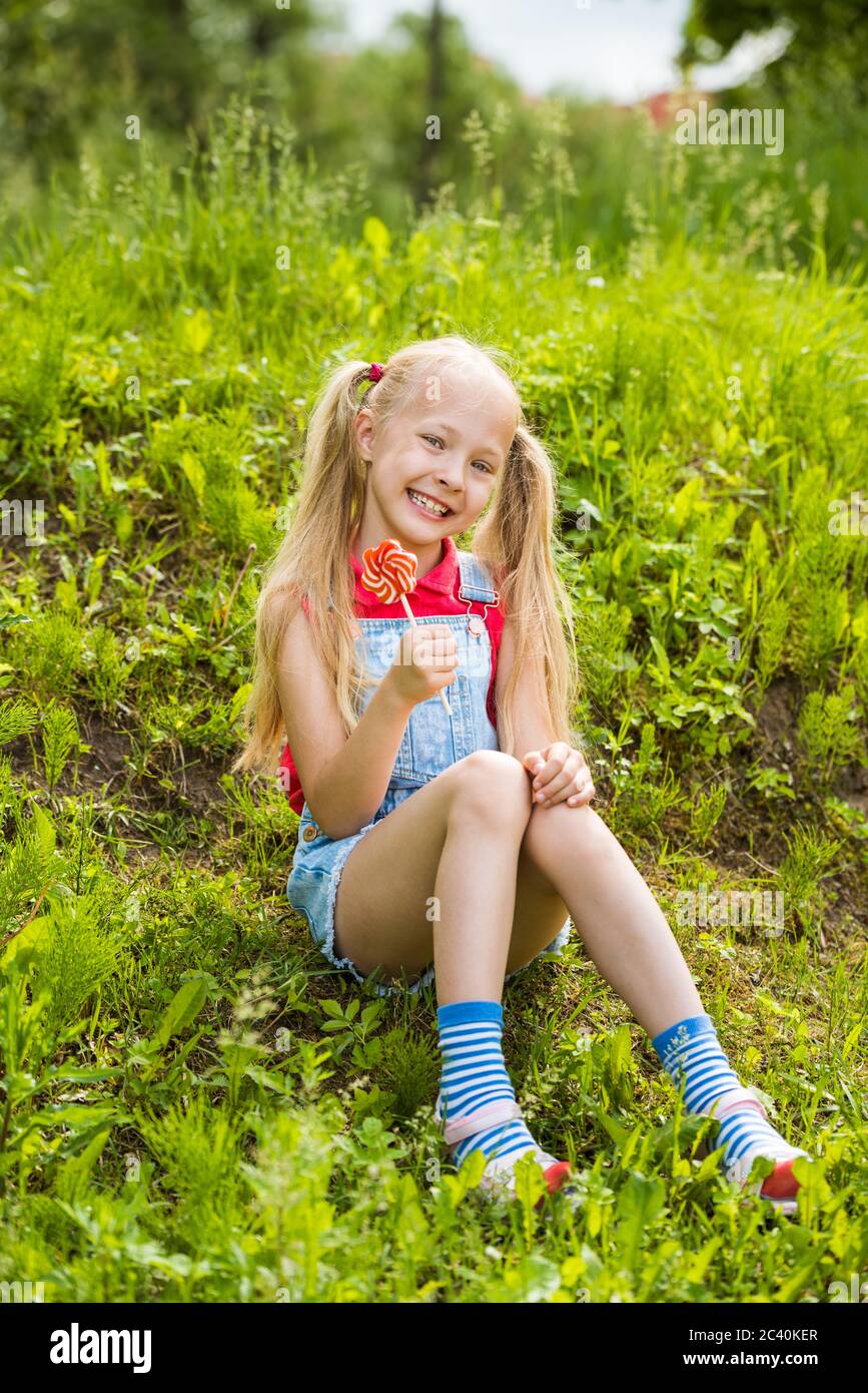 Blonde little girl with long hair and candy on a stick Stock Photo