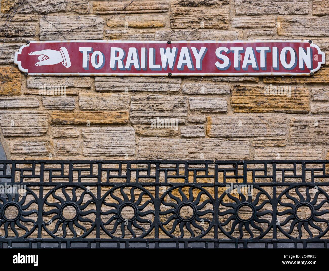 Old fashioned vintage sign on wall with hand pointing to railway station, England, United Kingdom Stock Photo