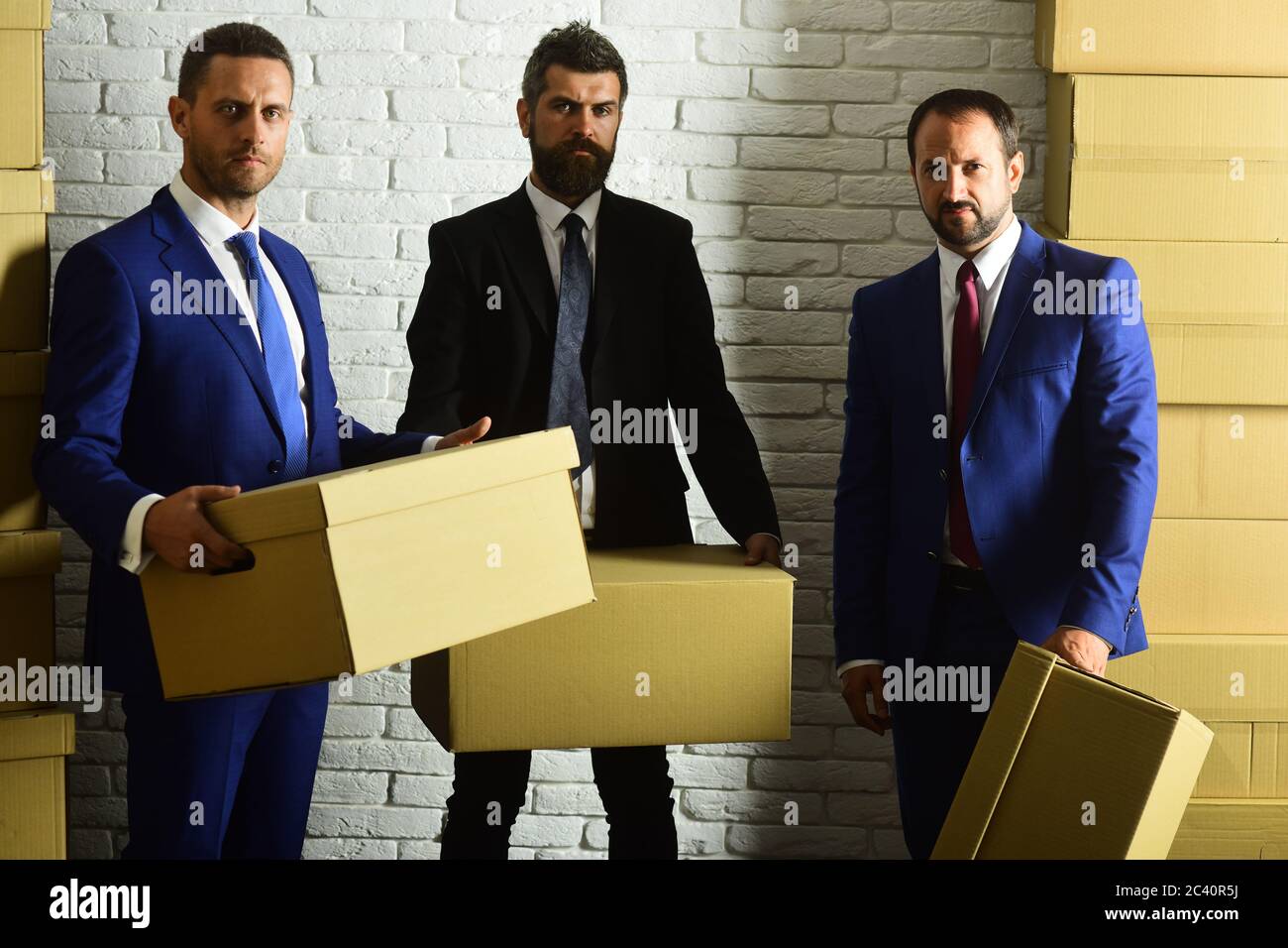 Managers hold big carton boxes on brick wall background. Business and