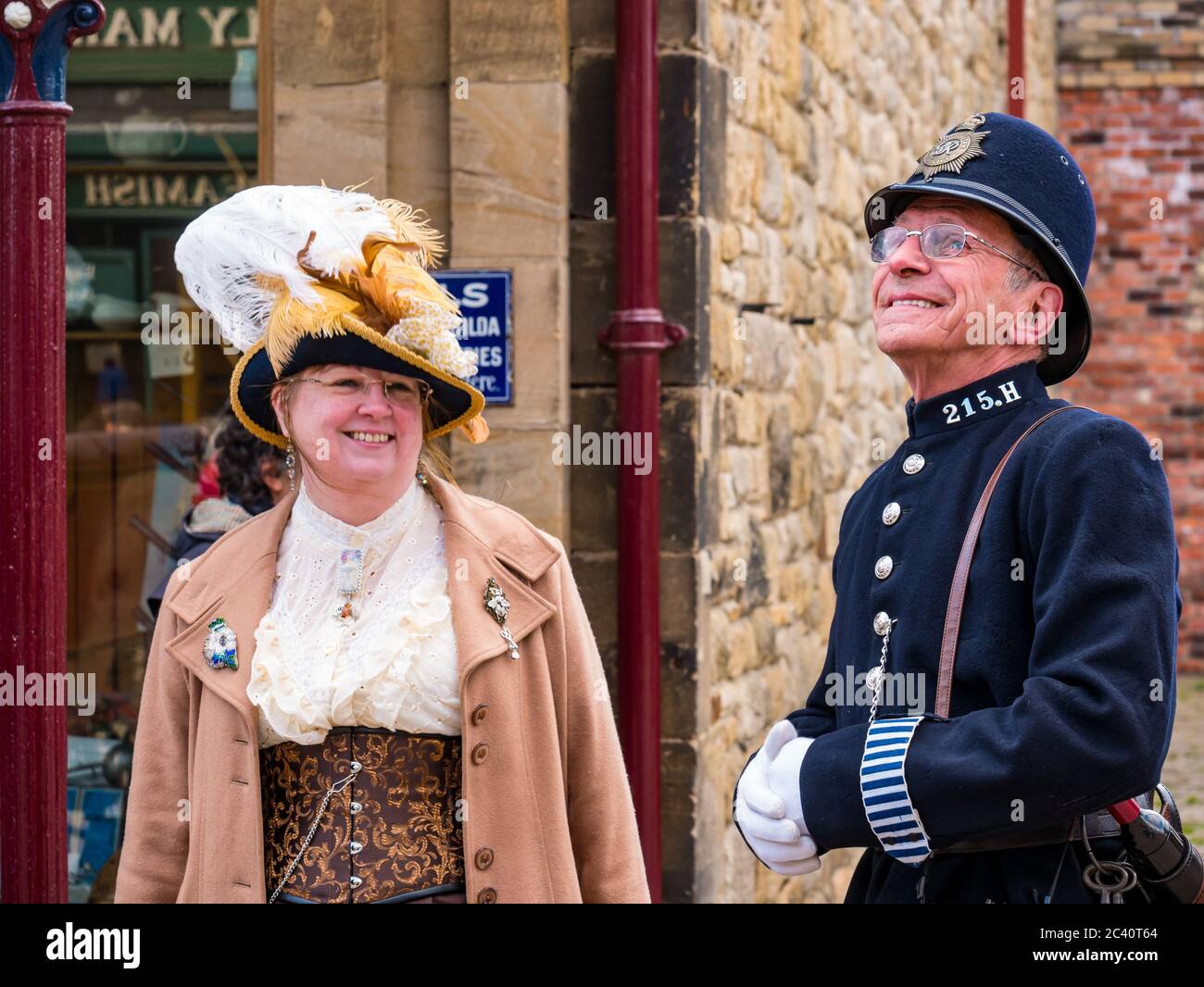 People dressed in period costume with man in  old fashioned police uniform and woman with feathered hat, Beamish Museum, Durham County, England, UK Stock Photo