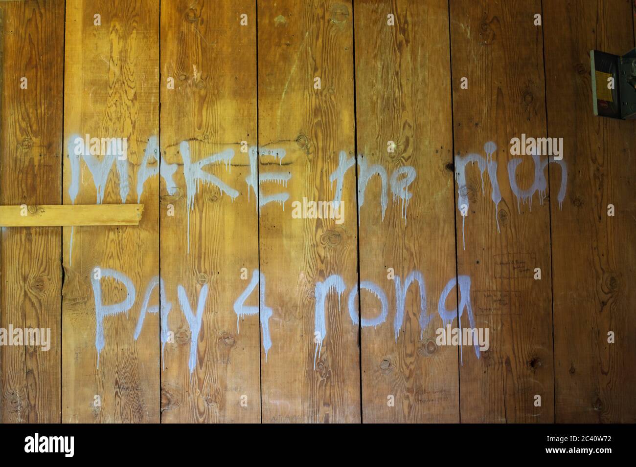 Graffiti inside a building that reads 'make the rich pay 4 rona'. Stock Photo