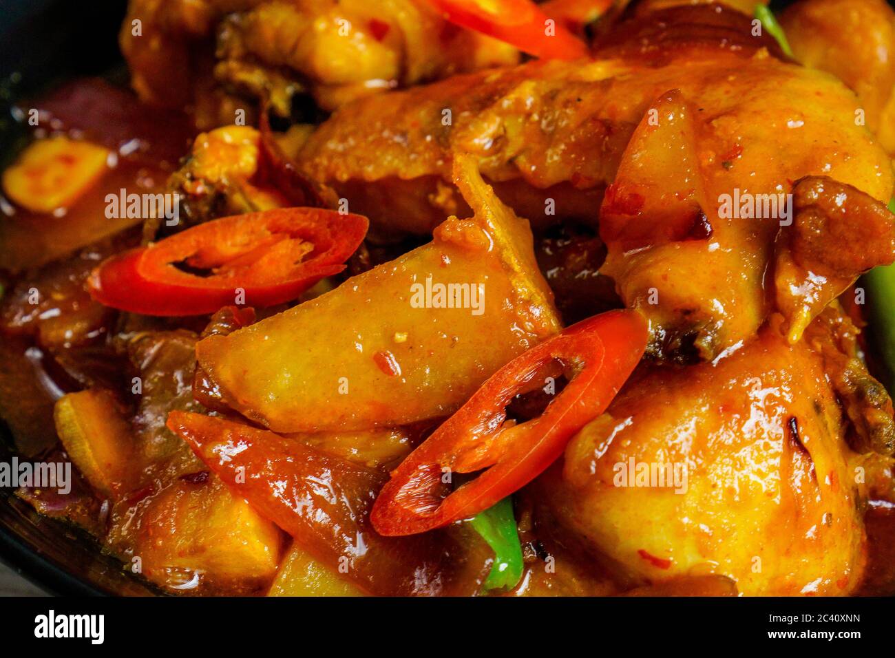 Fried chicken cooked with spicy sweet and sour sauce, thai chilli, red chilli and potatoes. Stock Photo