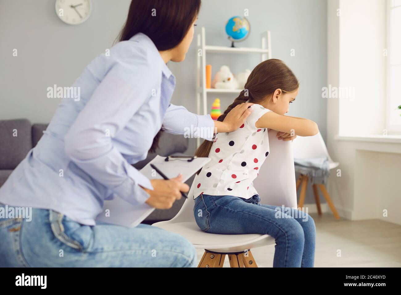 Child psychologist psychology. Woman psychologist with a clipboard helps a child with a problem in the room. Stock Photo