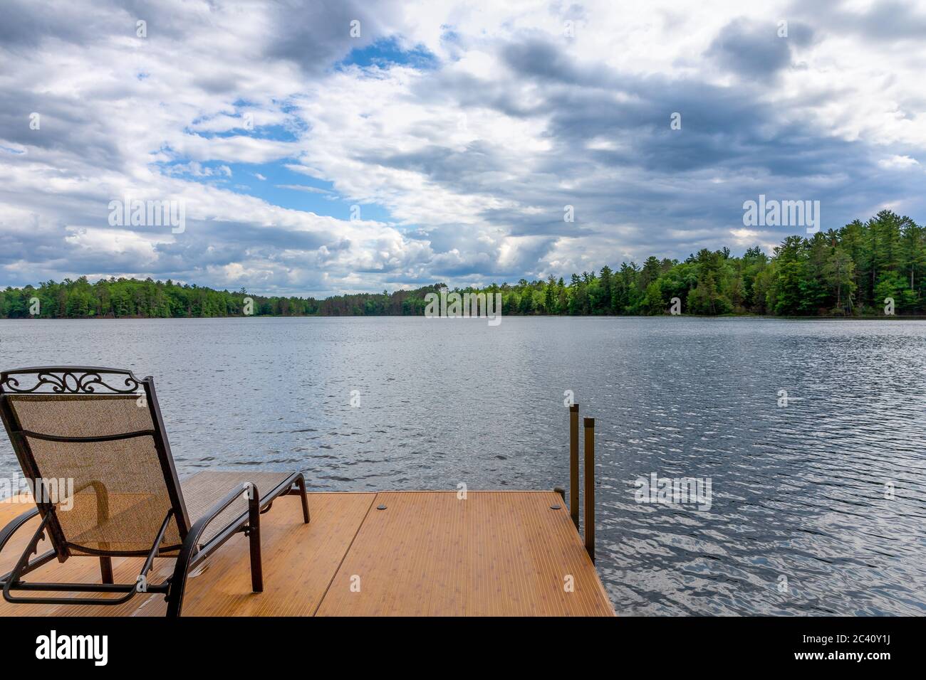 Beach chair on a dock in a Northwoods lake.  Ample copy space in sky if needed. Stock Photo
