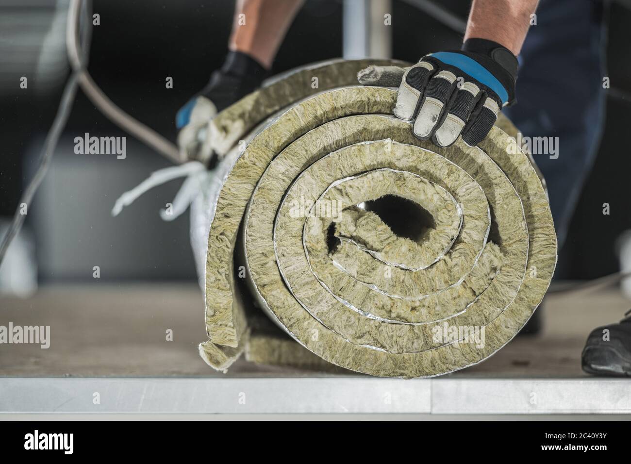 Construction Worker Preparing Roll of Mineral Wool Insulation to