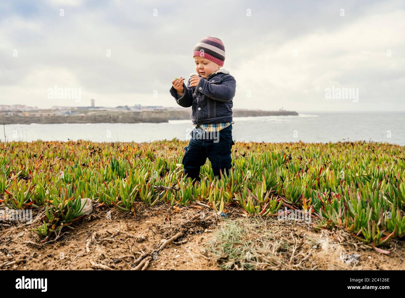 Toddler exploring nature on beautiful coast of Papoa islet in Peniche, Leiria district, Portugal Stock Photo