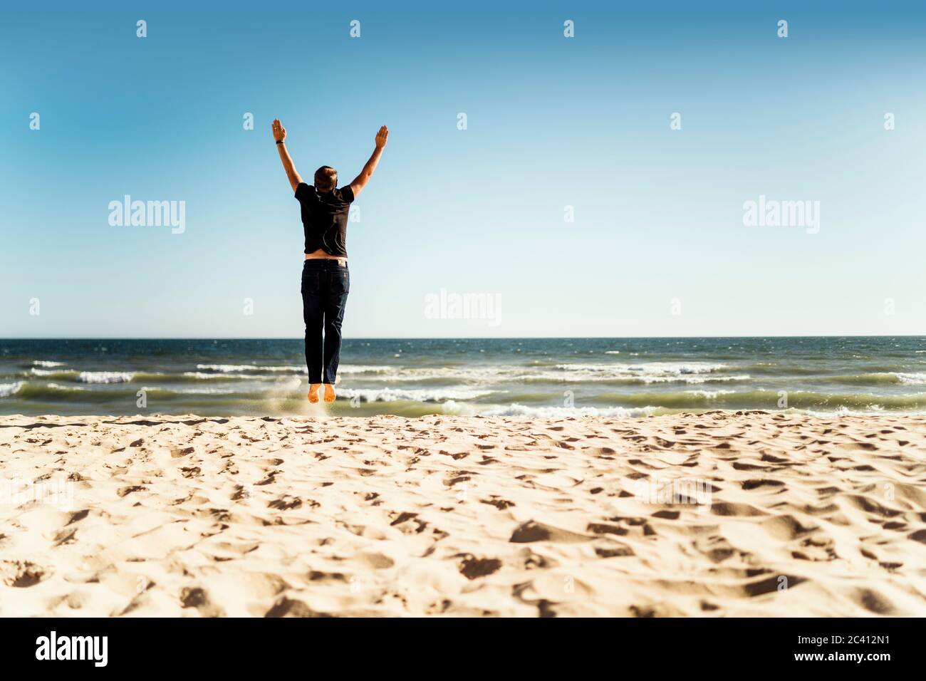 Man jumping on the beach with hands up Stock Photo