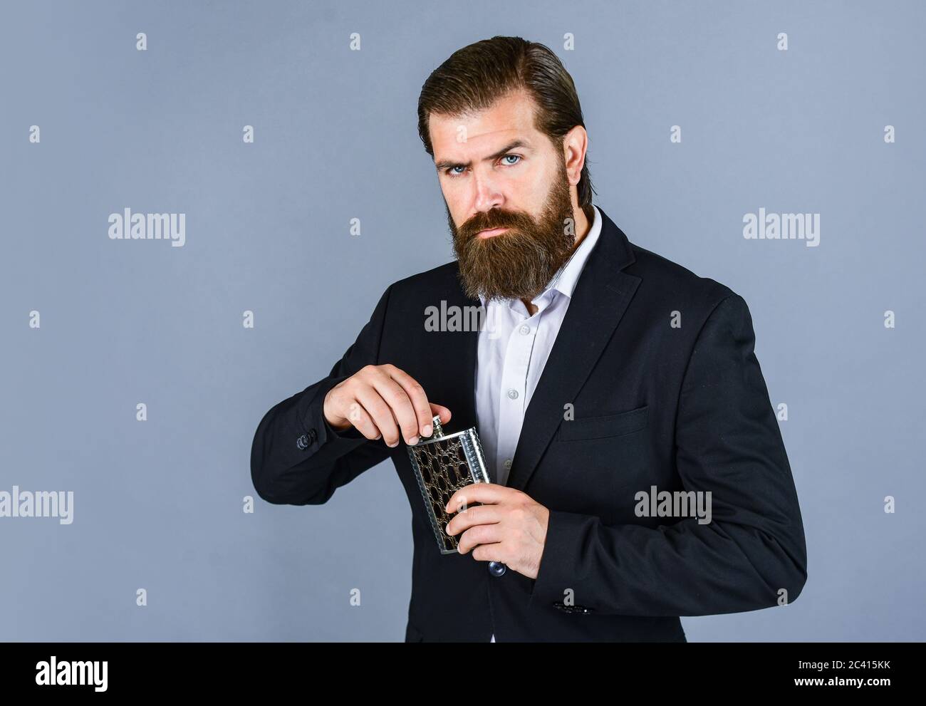 Have alcohol drink with you. Always with me. Flat metal bottle for alcohol. man with elegant look. hipster in suit hold metal flask for alcohol. Alcoh Stock Photo