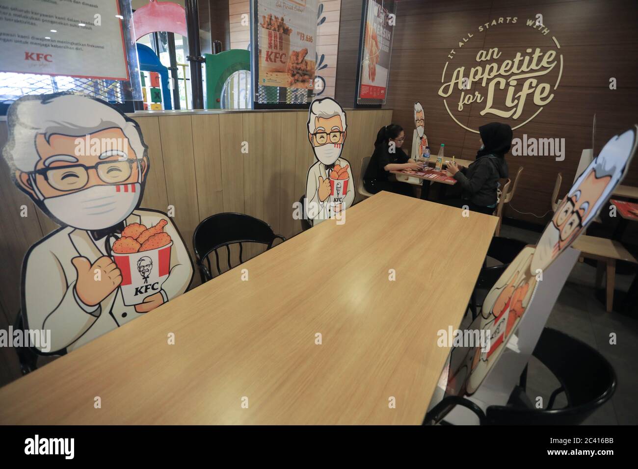 South Jakarta, Indonesia. 23rd June, 2020. Colonel Sanders' characters mounted at tables as a way of maintaining the social distance, a precaution against the spread of coronavirus (covid-19) at KFC. Credit: SOPA Images Limited/Alamy Live News Stock Photo