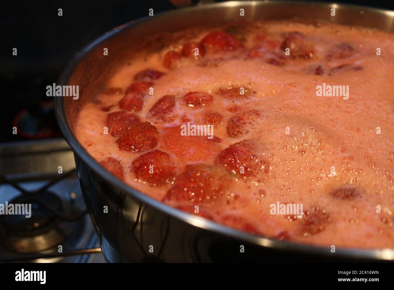 Strawberry jam being made at home reaching a rolling boil Stock Photo