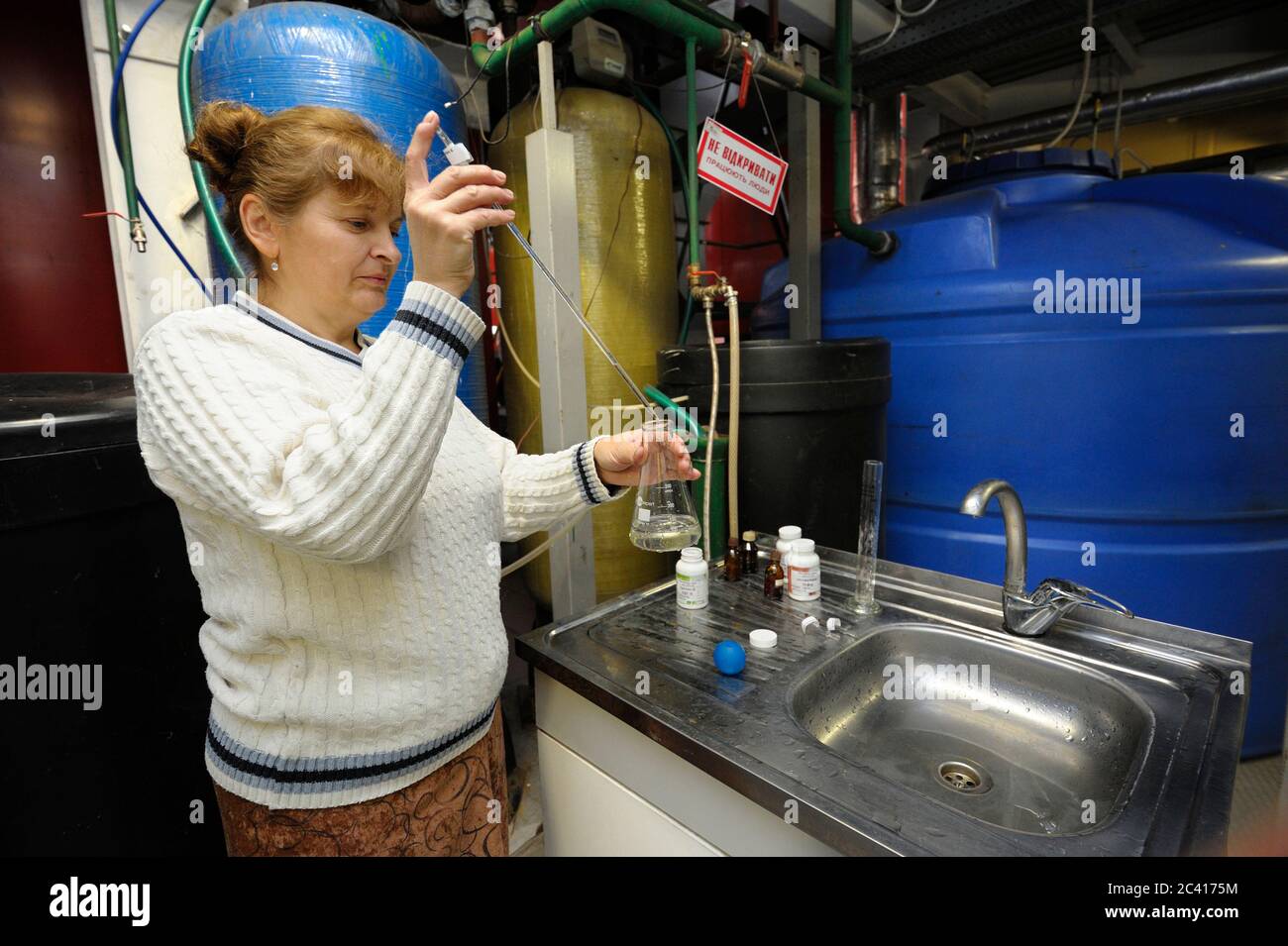 Female chemist checking quality of water supplied to steam generation