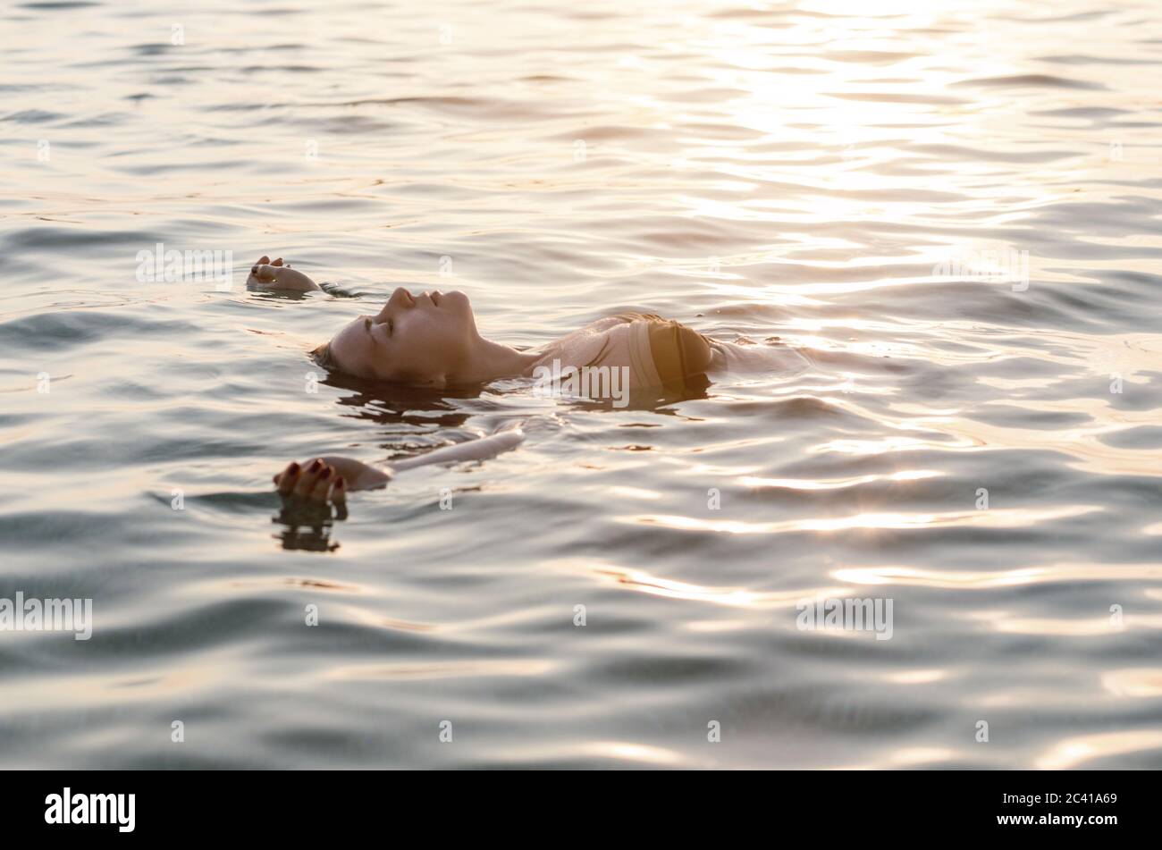 Young woman floating on back in the sea Stock Photo