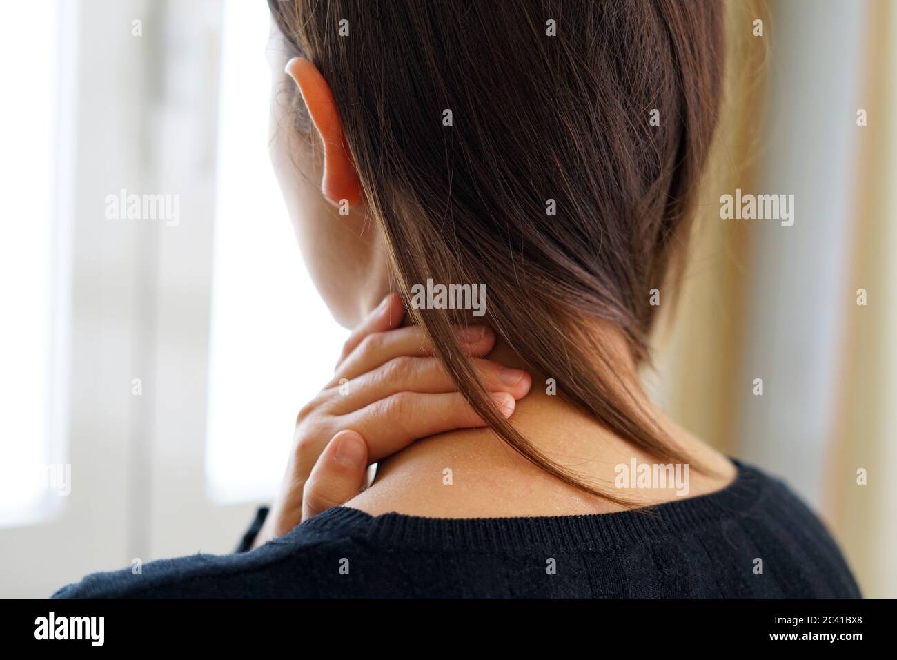 Woman with neck pain touching her neck. Neck pain concept. Stock Photo