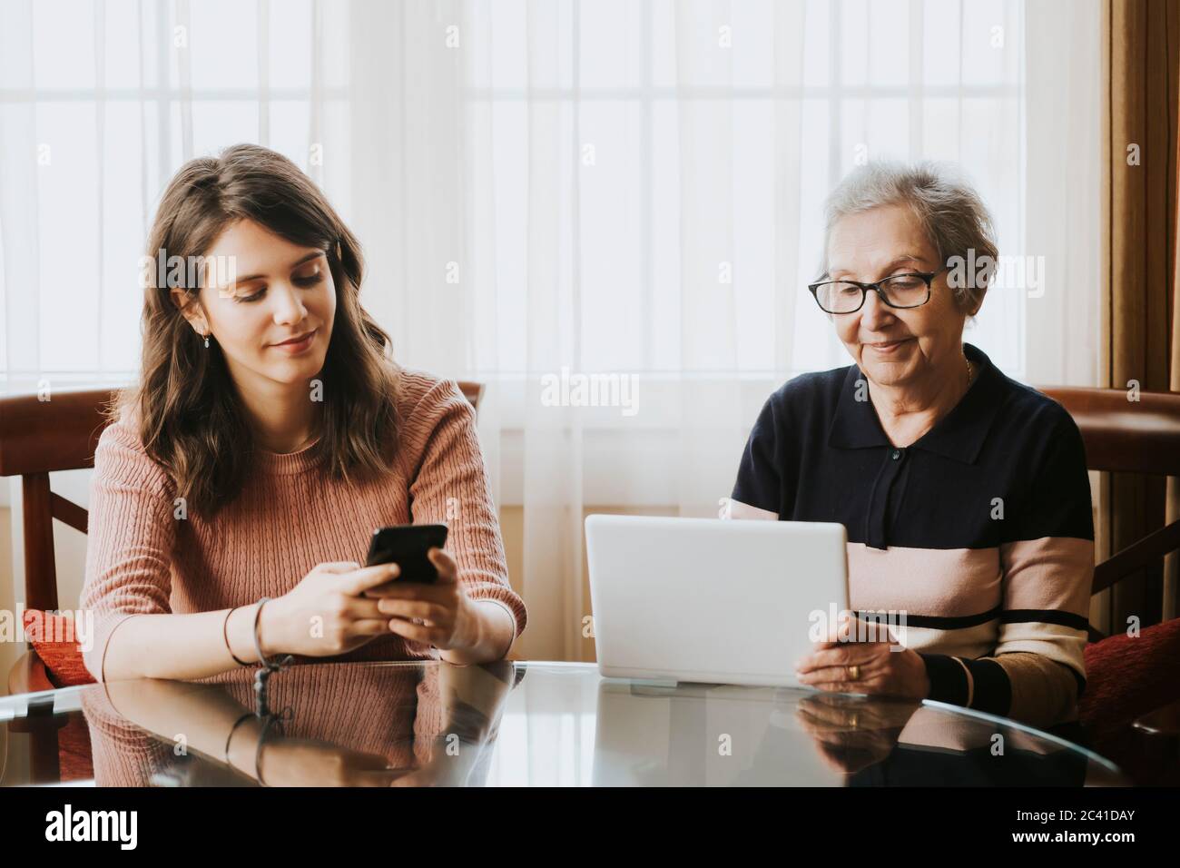 granddaughter using mobile and grandmother using tablet Stock Photo