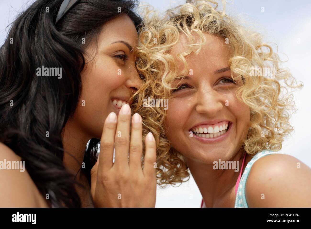 Two young women whisper together - girlfriends - leisure time Stock ...