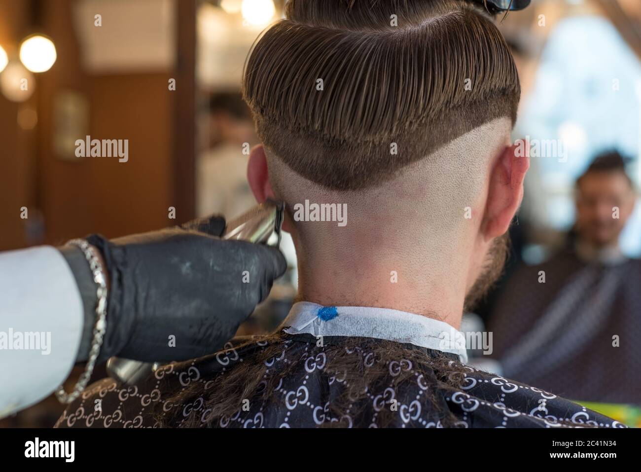 a hairdresser cuts a bearded young guy with a hair trimmer, combing the hair  on his head. Work of the master in men's haircut in a barbershop Stock  Photo - Alamy