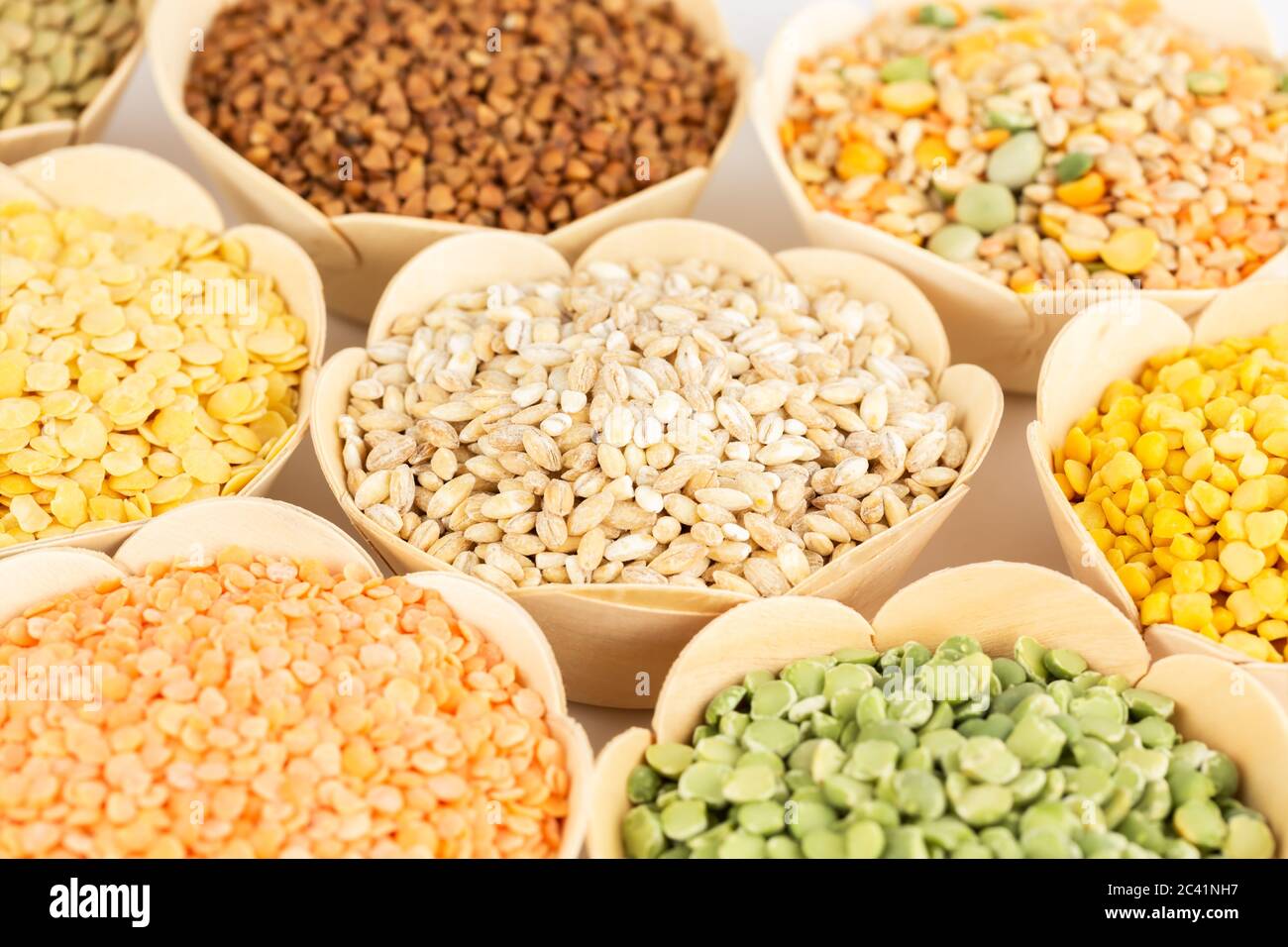 The collection of different groats in the bamboo bowls. Wheat, buckwheat, peas and lentils. Stock Photo