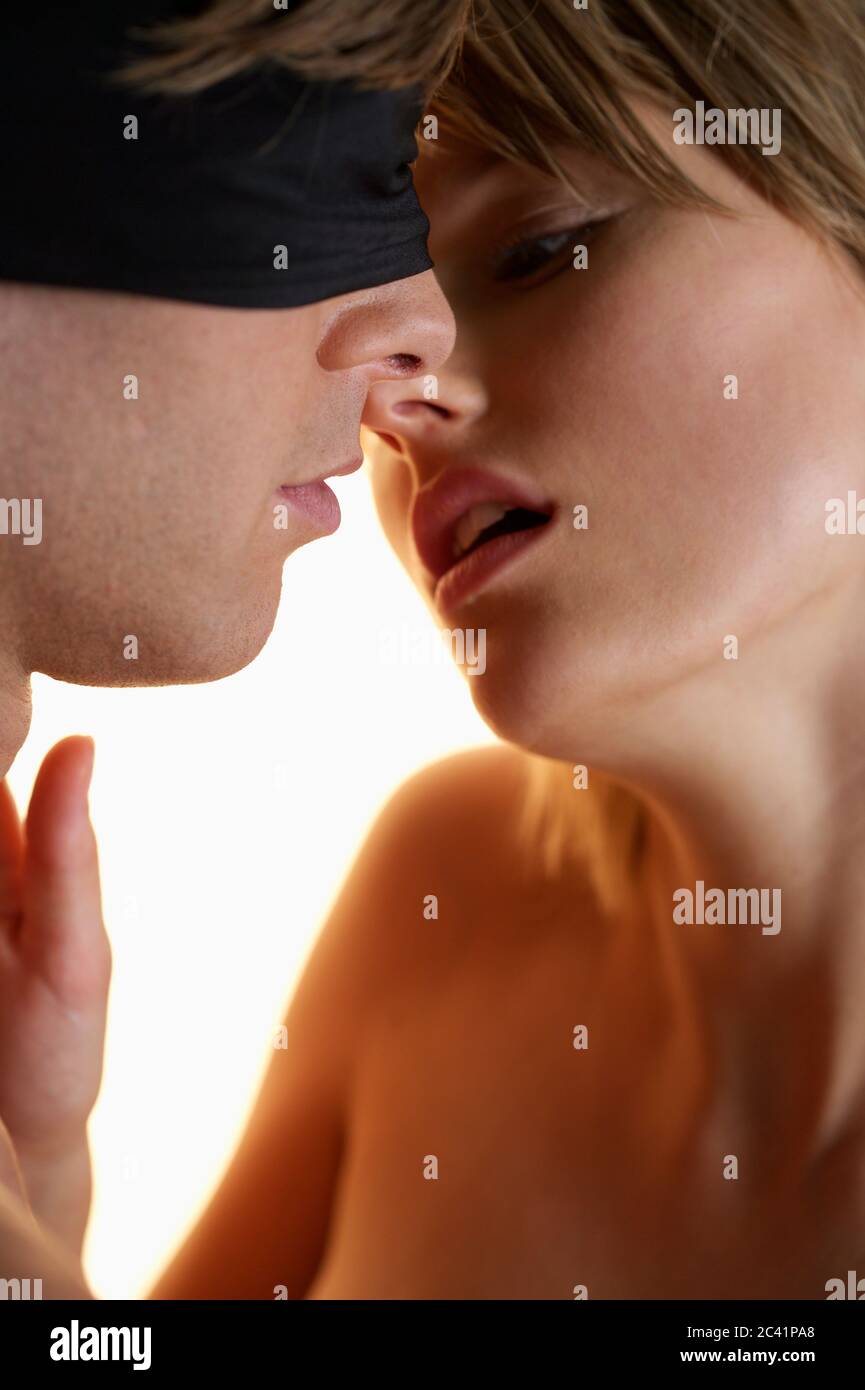 Young woman kisses young man with blindfold Stock Photo - Alamy