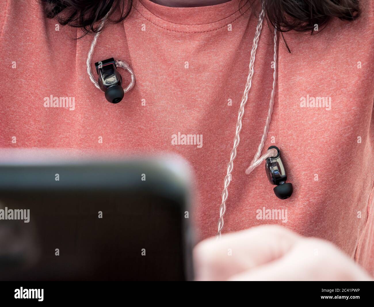 Man wearing intra auricular headphones around his neck. Headphones with