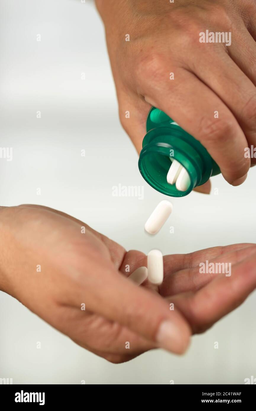 Person sprinkles pills on hand medication addiction illness Stock