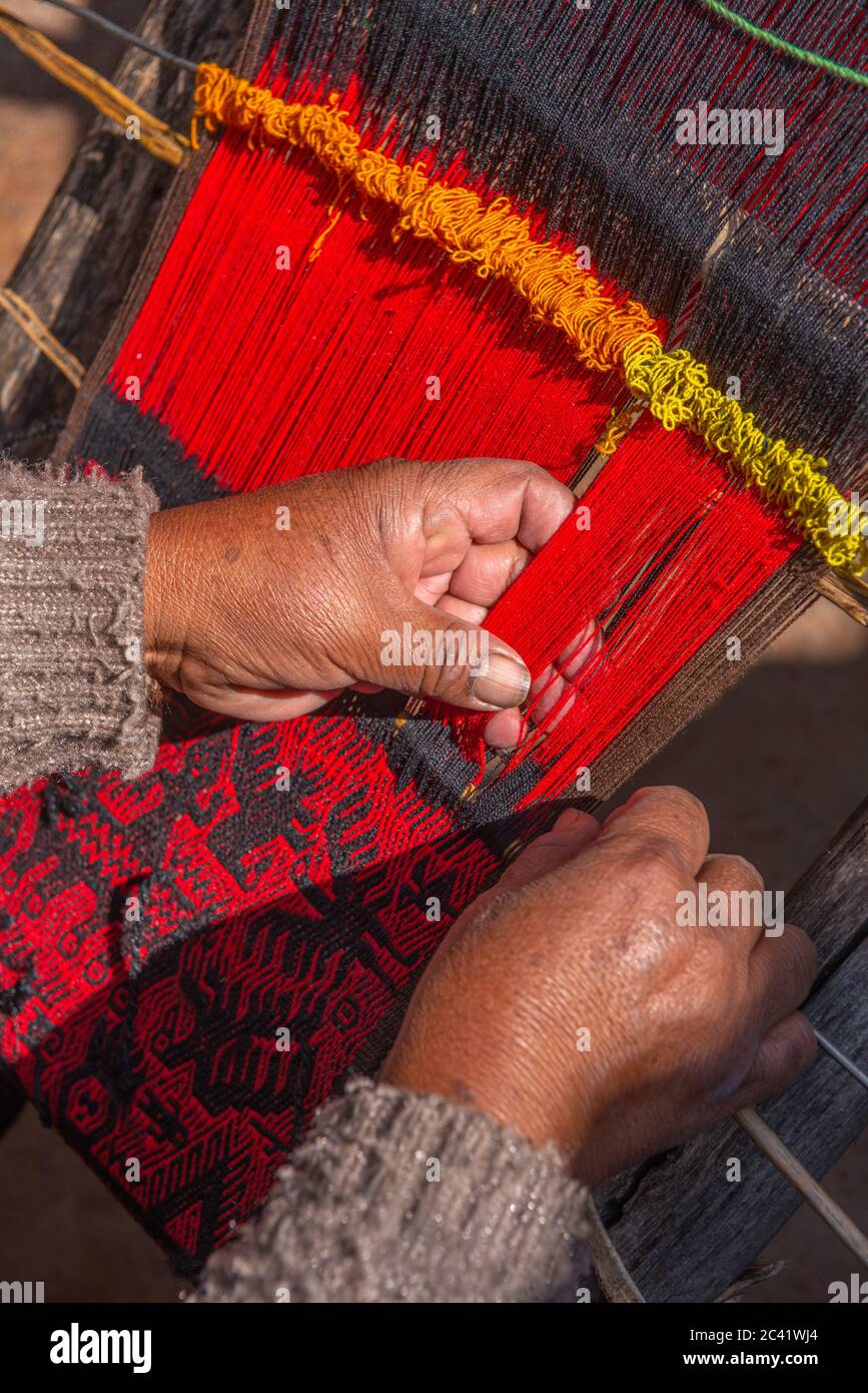 Elderly woman weaver weaving local red and black Jalq´a art pattern