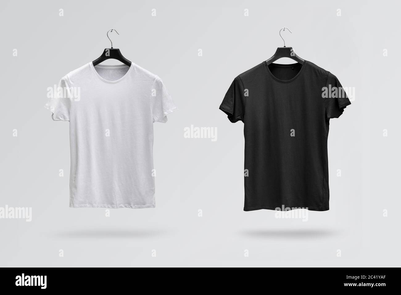 Front sides of male black and white cotton t-shirts on a hanger isolated on white background. T-shirts without print Stock Photo