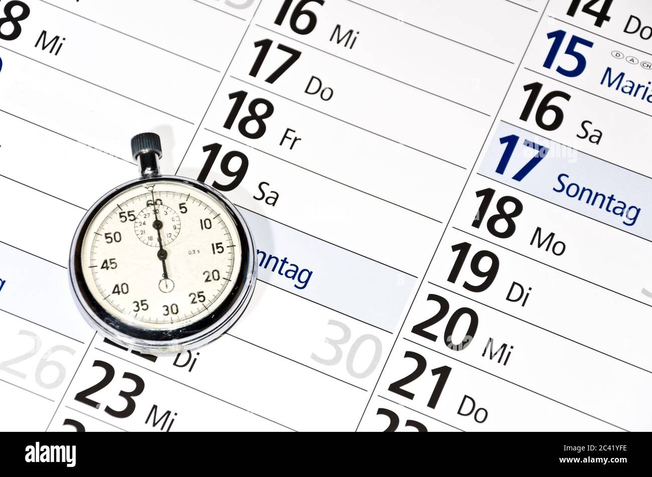 Stopwatch lying on calendar (with captions of the days of the week in German) Stock Photo