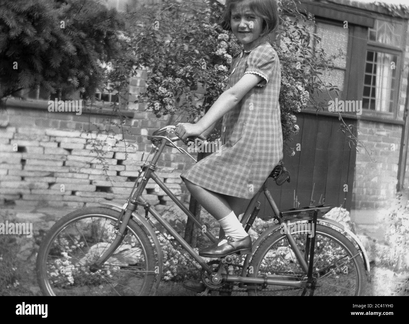 1940s, historical, a young girl wearing a summer dress, short socks and  shoe outside sitting on her bicycle, England, UK Stock Photo - Alamy