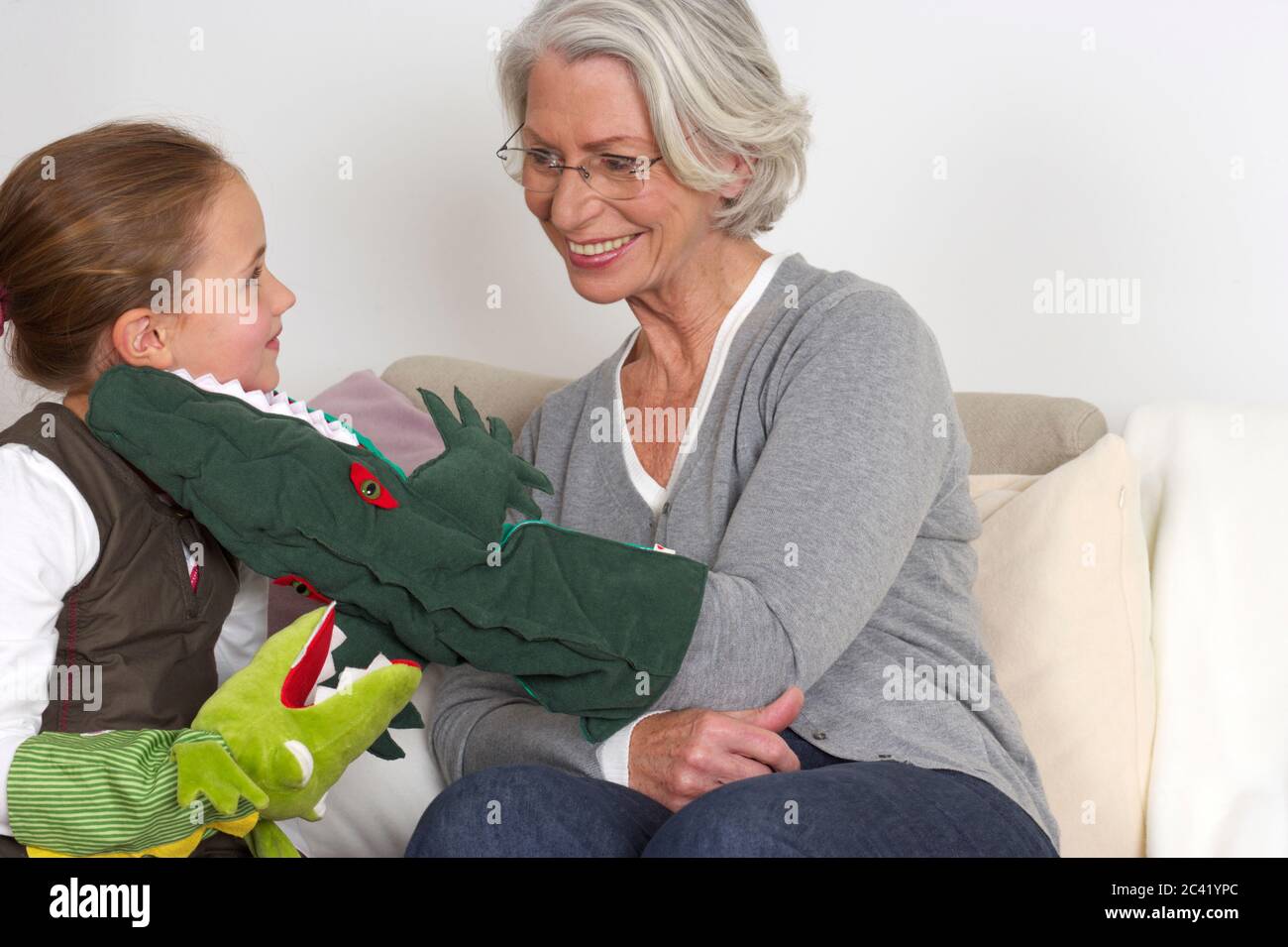 Little girl and her grandma play with hand puppets - leisure - togetherness Stock Photo