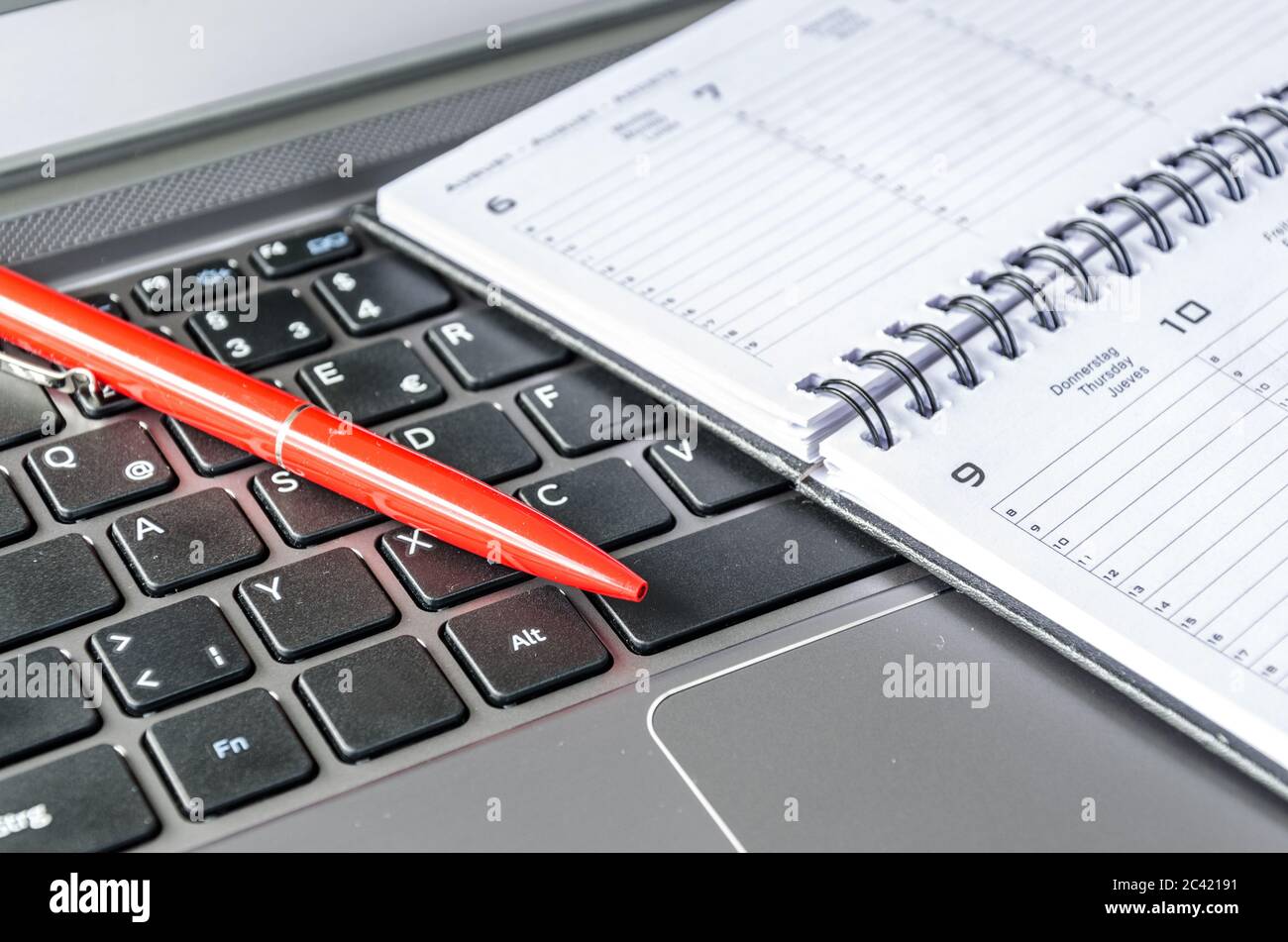 Red pen and schedule lying on computer keyboard Stock Photo