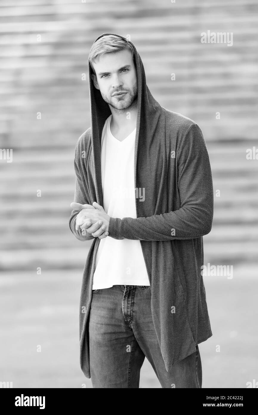 Male fashion influencer. Fashionable young model man. Carefree guy street  style outfit with hood. Handsome man with hood standing urban background.  Fashion trend. Comfortable clothes for daily wear Stock Photo
