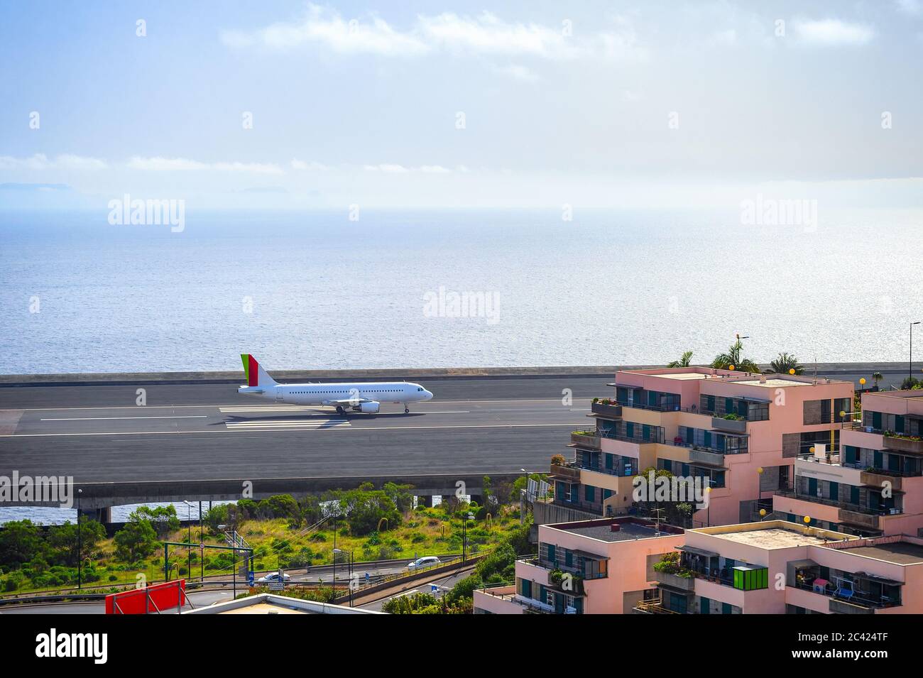 Airplane landing at runway of Funchal airport by Atlantic ocean in sunset light, apartment blocks in foreground, Madeira, Portugal Stock Photo