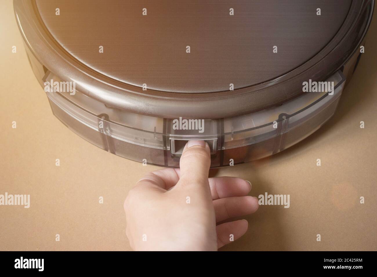 Woman cleans trash bin automatic robot vacuum cleaner. Modern smart