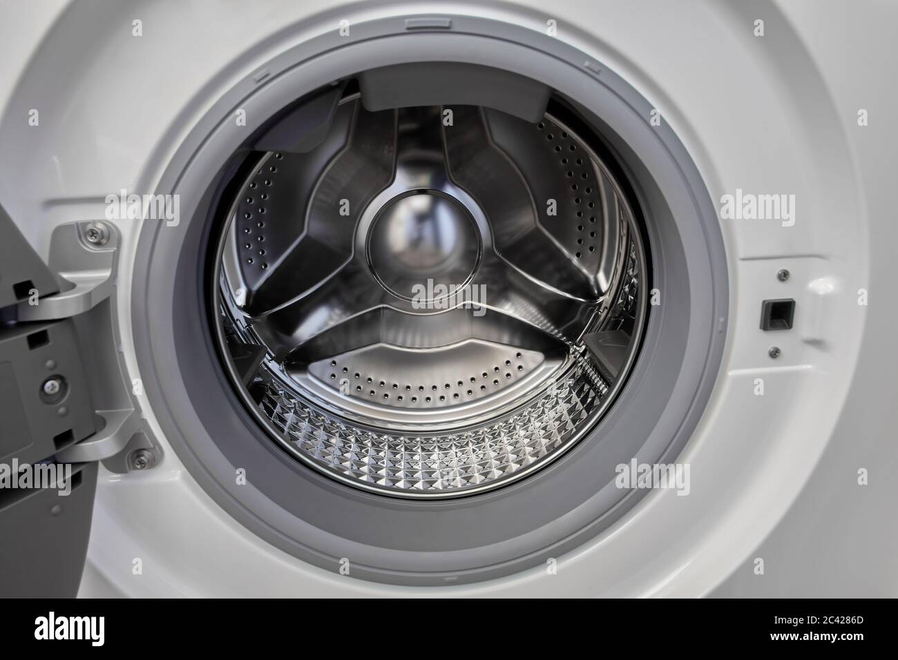 The open door of the automatic washing machine shows an empty steel inner drum. Diamond design running on these drums. Stock Photo