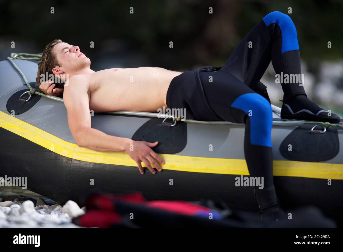 Young man in a wetsuit lies on an inflatable boat relaxation white