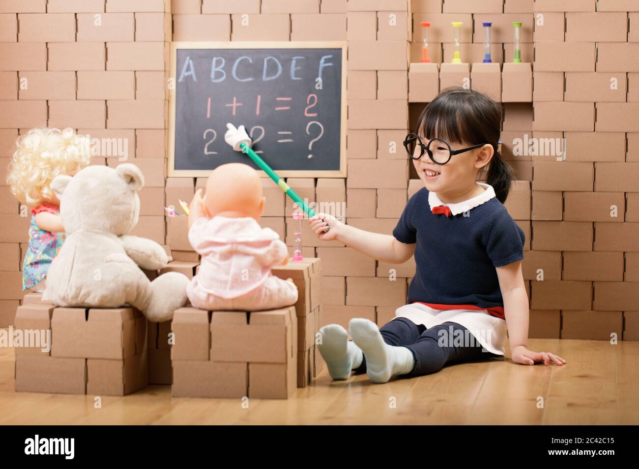 toddler girl pretend play as a teacher at home Stock Photo