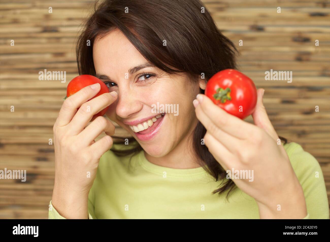 Middle-aged woman holds two tomatoes in front of her eyes Stock Photo ...