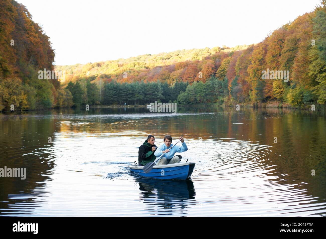 Two men paddle in a boat across a lake Stock Photo - Alamy