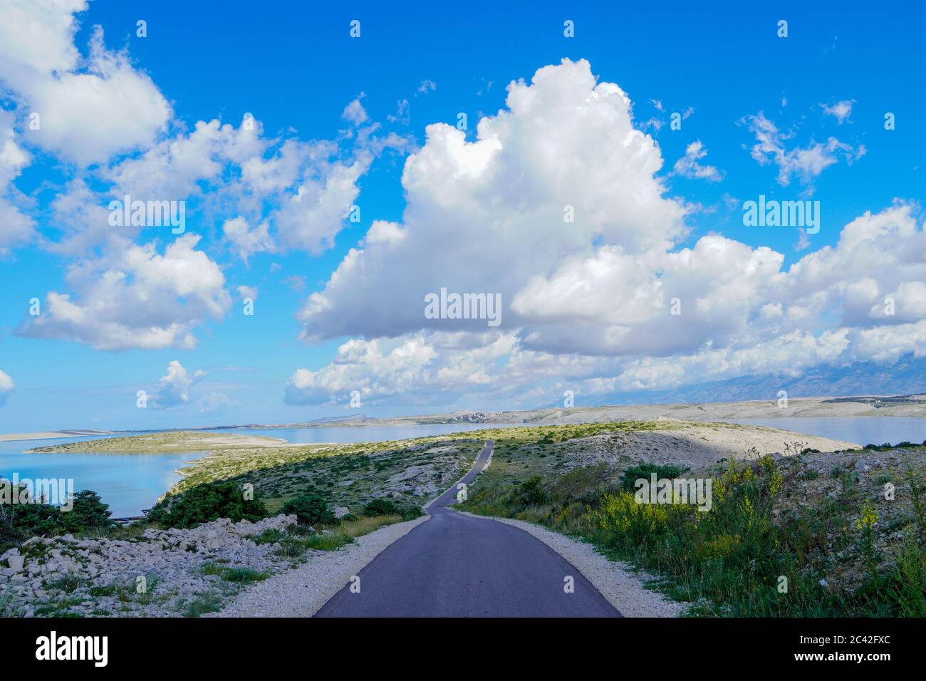 Mountain road at sunrise. Sunny sky with blue clouds and a beautiful asphalt road in summer. Vintage toning. Travel background. Scenography on the hig Stock Photo