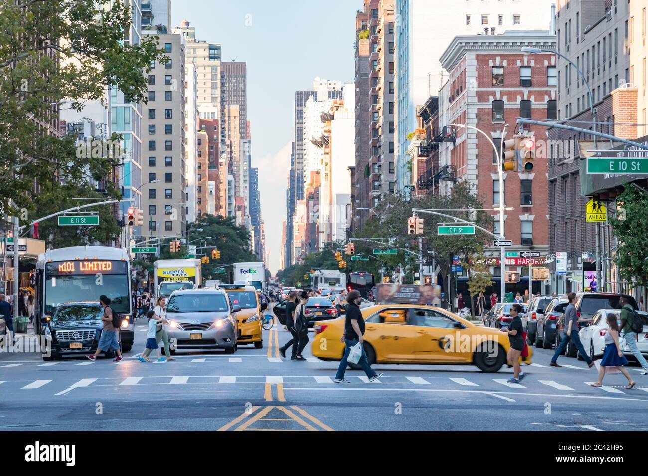 NEW YORK CITY, USA 2017: Busy people walk across an intersection at rush hour on 3rd Avenue in front of the cars stopped at a traffic light in Manhatt Stock Photo