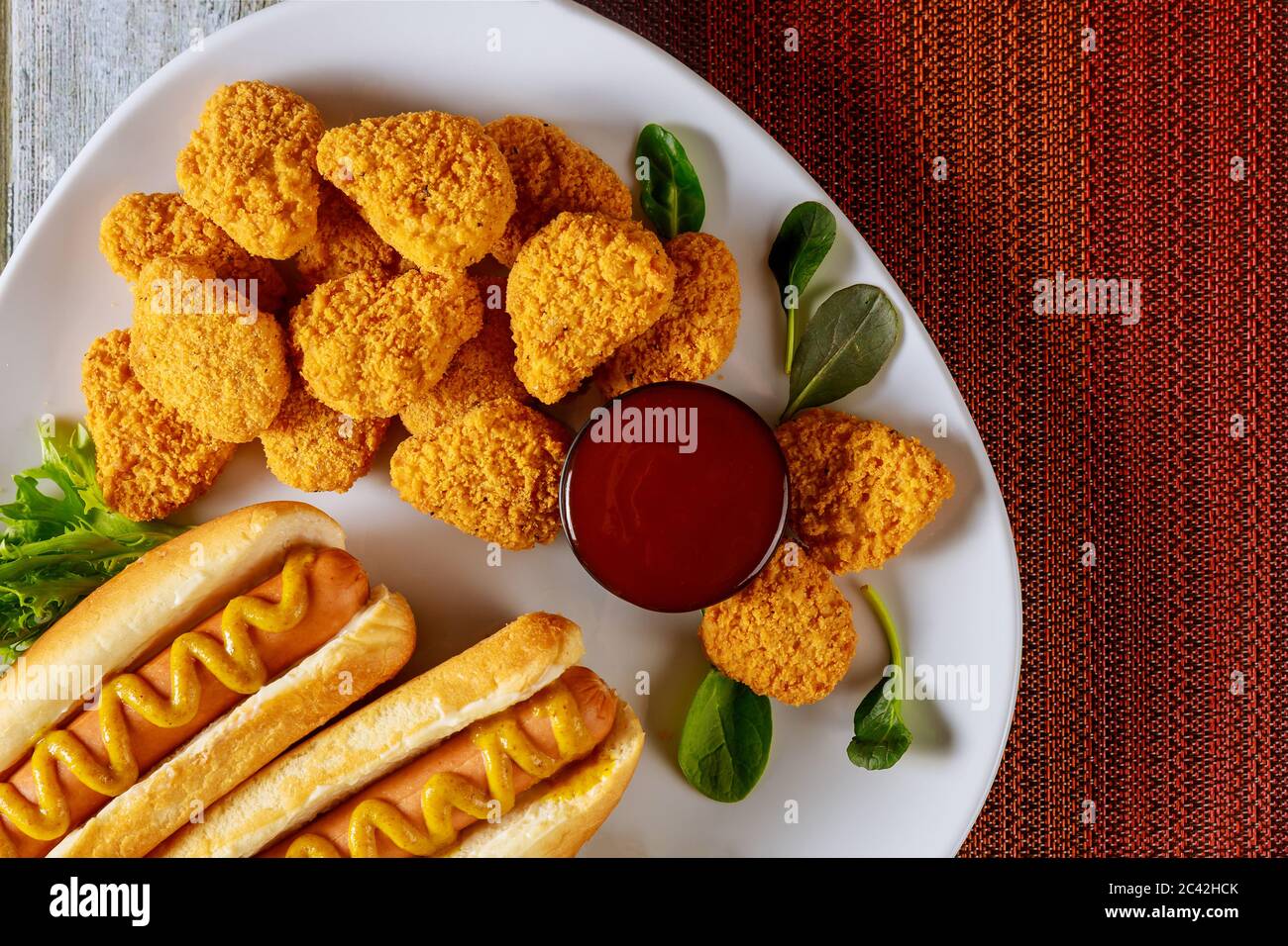 Chicken nuggets with ketchup and hot dog with mustard on white plate. Fast food concept Stock