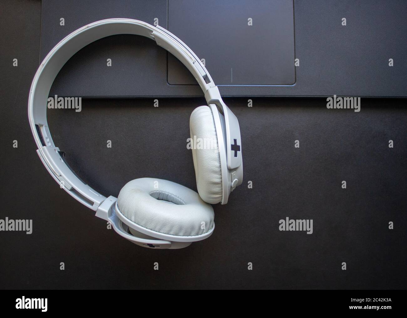 Wireless headphone resting on a laptop on a office desk Stock Photo - Alamy